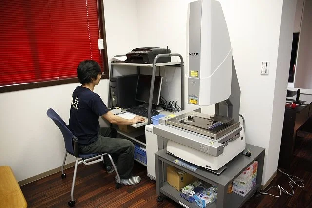 測定器を手に取り加工寸法を確認している作業者の横顔